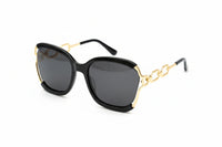 Black sunglasses with gold accents on a beige background