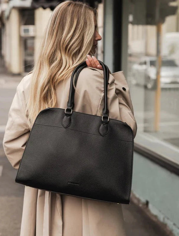Woman holding a black laptop bag in an urban setting